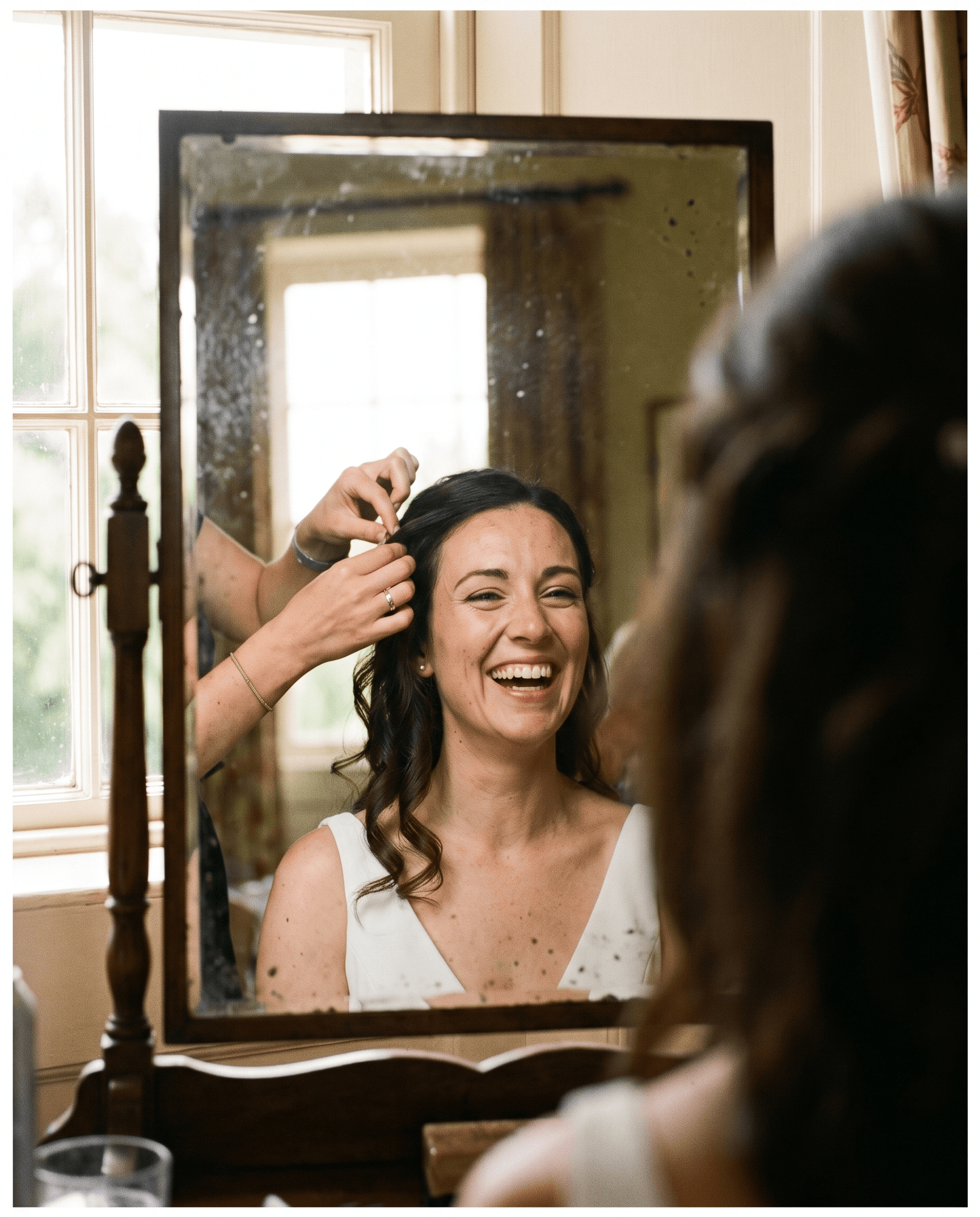 A bride having her hair finished before a mirror